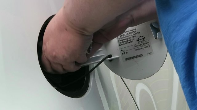 Woman's hand opening petrol cap on white car