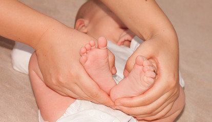 newborn baby feet on female hands, shape like a lovely heart