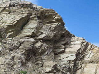 Laminated structure of mountain rock over blue sky