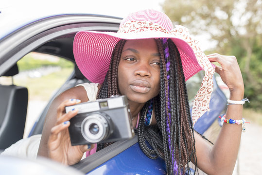 Beautiful african woman takes pictures from the car window.