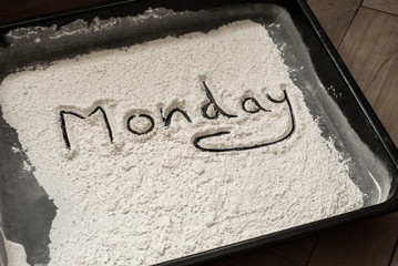 Monday Word Written on Baking Sheet Covered with White Flour