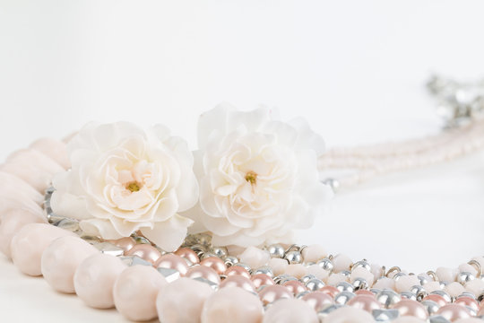 Close up of pastel pink beaded necklace with miniature rose flowers. Soft pastel dreamy photograph.