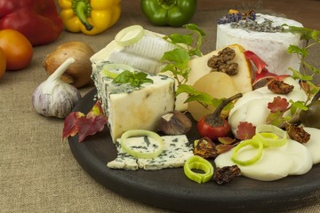 Various types of cheese on a cutting board, made from milk. Dairy products. Moldy and smoked cheese, preparing home-made snacks.
