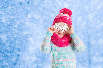 Little girl playing with toy snow flakes in winter park