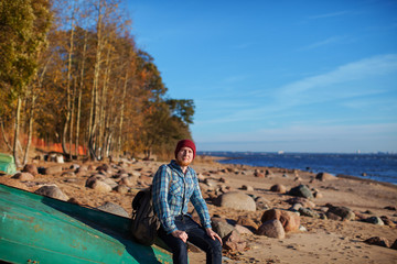 a man with a backpack sitting in a boat on a rocky beach in autumn