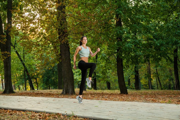 Obraz premium A young beautiful girl is running into the park on cool season a