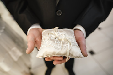 wedding rings in bridal hands in pad on ribbon