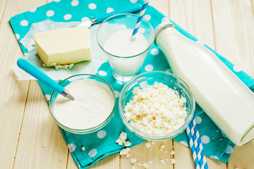 A light breakfast of milk products , cottage cheese, sour cream and milk, roll and butter on a wooden background