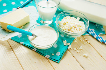 A light breakfast of milk products , cottage cheese, sour cream and milk, roll and butter on a wooden background