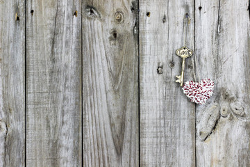 Skeleton key and rope heart hanging on rustic wood door