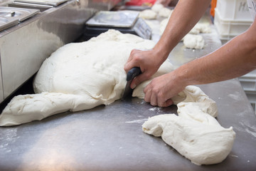Man preparing dough for pizza in pizzeria