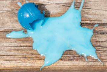 A blue paint ball that has burst or exploded on a wooden background