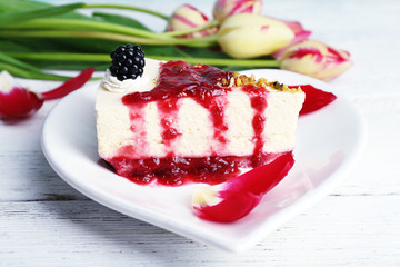Tasty piece of cheesecake with berry sauce on plate on table close up