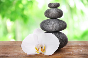 Stack of spa stones with orchid flower on blurred nature background