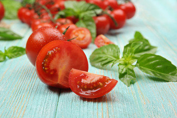 Fresh tomatoes with basil on wooden table close up