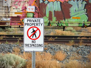 private property no trespassing sign with graffiti covered train in background - obrazy, fototapety, plakaty