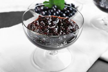 Tasty currant jam with berries on table close up