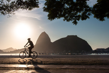 Silhouette of a Man Cycling in the Early Morning during Beautiful Warm Sunrise in Rio de Janeiro