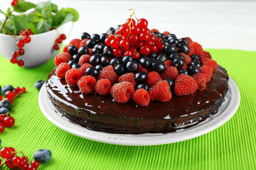Delicious chocolate cake with summer berries on green tablecloth, closeup