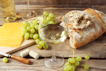 Still life of wine, grape, cheese and bread on rustic wooden background