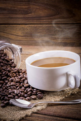 Coffee cup and beans on a wooden table.