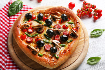 Heart shaped tasty pizza and red checked cotton serviette on wooden background