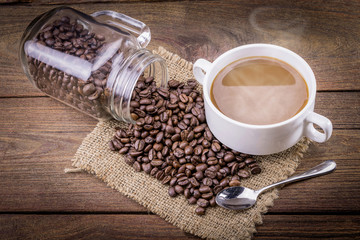 Coffee cup and beans on a wooden table.