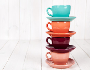 Colorful coffee cups on white wooden background