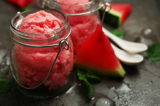 Watermelon ice cream in glass jars on dark background