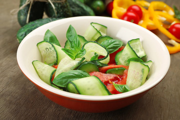 Vegetable salad with cucumbers on wooden background