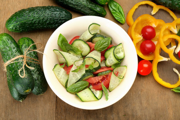 Vegetable salad with cucumbers and pepper on wooden background