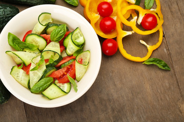 Vegetable salad with cucumbers and pepper on wooden background