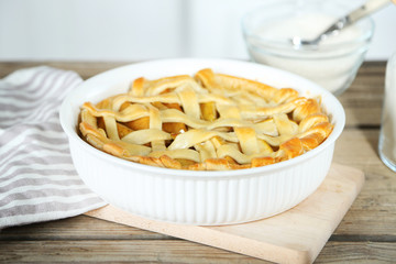 Homemade apple pie on wooden table, on light background
