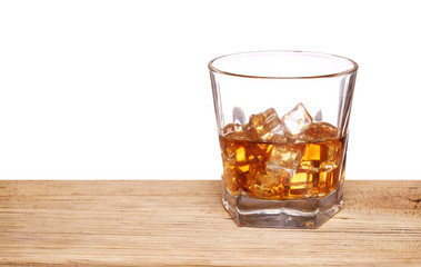 Glass of alcohol scotch whiskey with ice cube on wooden table and white background