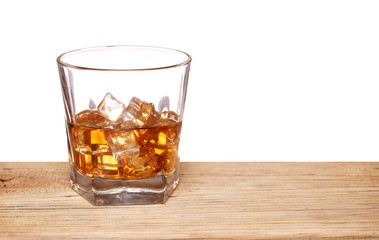 Glass of alcohol scotch whiskey with ice cube on wooden table an
