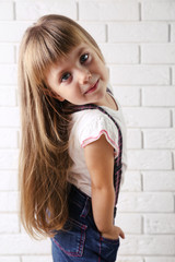 Beautiful little girl on light wall background