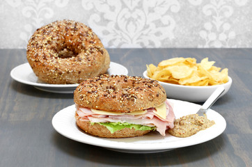 Ham, Swiss cheese and lettuce sandwich on a multi grain and seeded bagel.