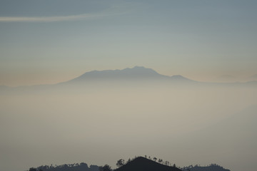 Foggy and volcano mountain during sunrise taken from Pinajagun II view point ,Indonesia.