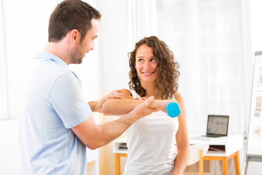 Young attractive woman doing exercise with physiotherapist