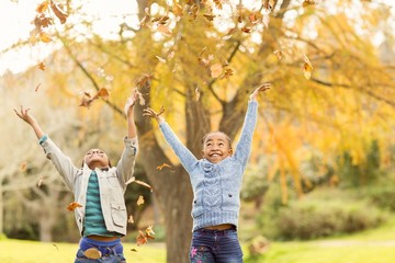 Portrait of young children throwing leaves around