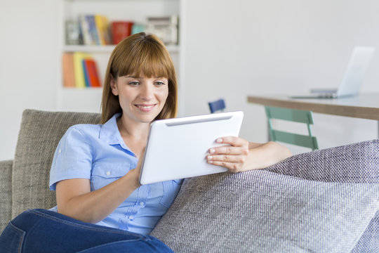Attractive woman using app digital tablet at home on couch