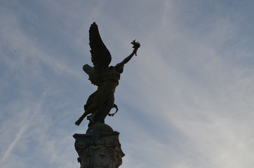 Statue of angel on a pillar against sky