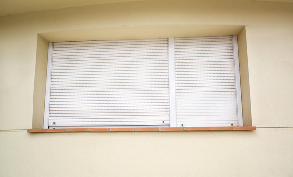 Window on the house completely covered with white horizontal bli