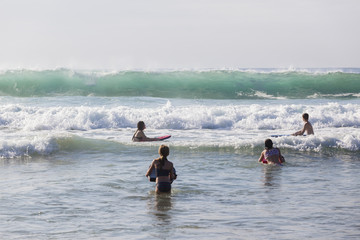 Teenagers Swimming Surfing  body boards in ocean waves shoreline