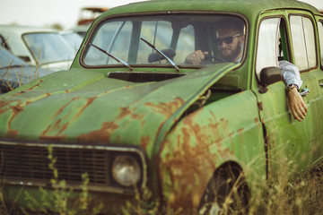 Young stylish handsome man, wearing shirt and sunglasses, drivin