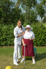 Senior Woman Standing With Crutch At Physiotherapy, Looking At Camera