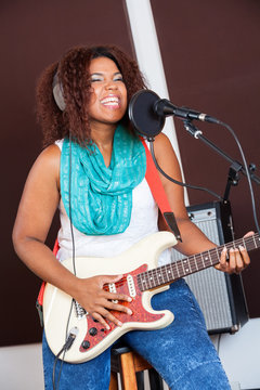 Female Singer Playing Guitar In Recording Studio