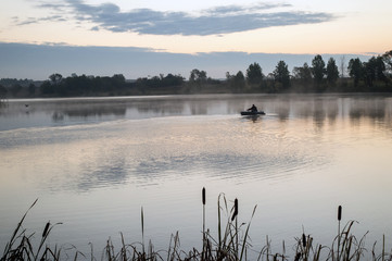 A fisherman in a boat sailing in the morning mist