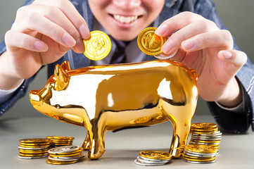 金の豚の貯金箱にお金を貯める男性