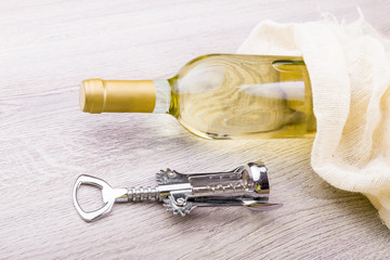 Wine bottle with corkscrew on wooden background